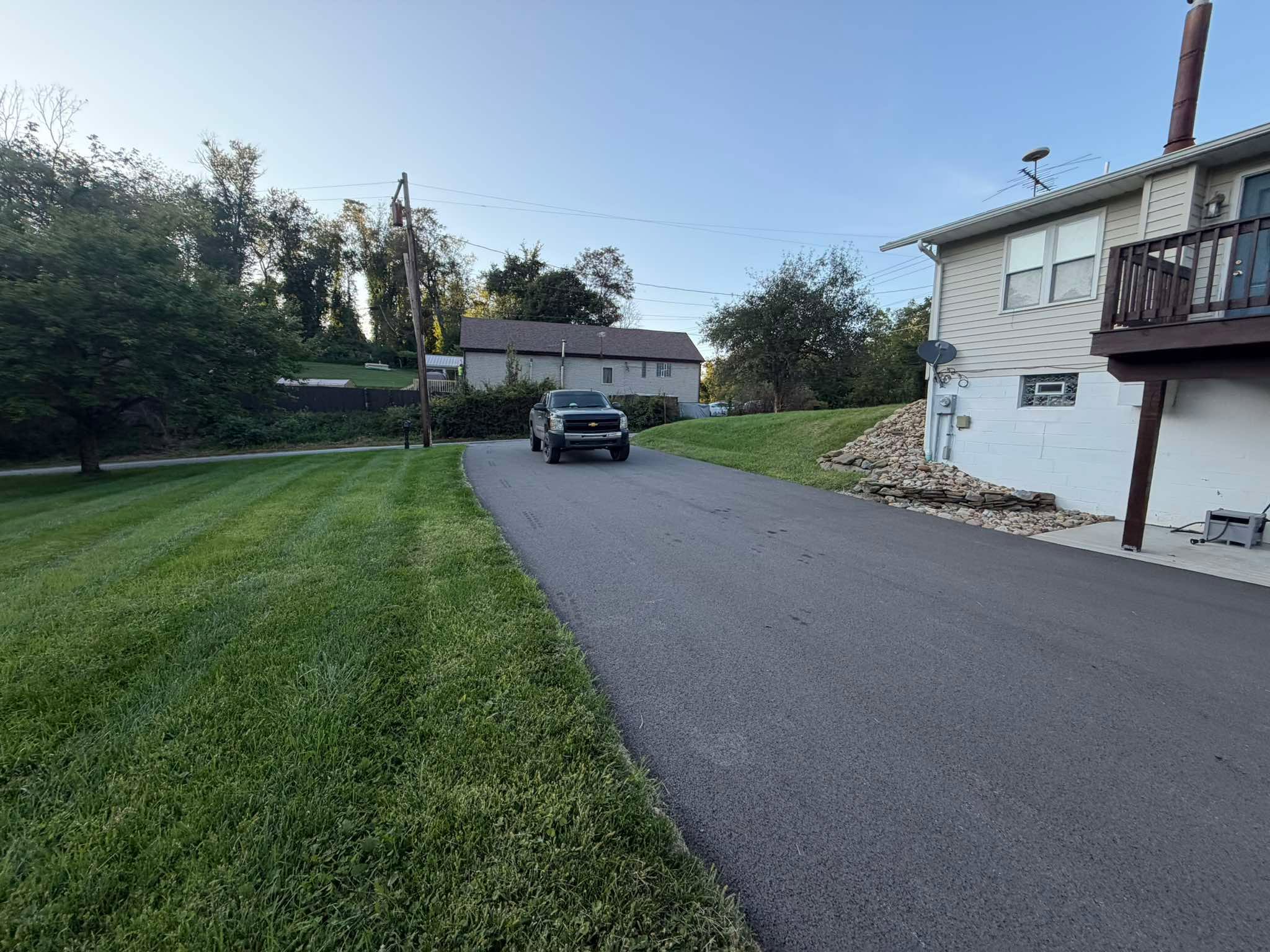Completed asphalt sealing project along a residential property